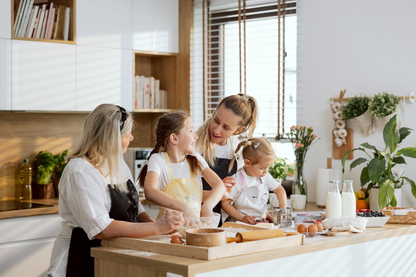 Grandmother, mother and two young girls baking together in a bright, sunlit kitchen